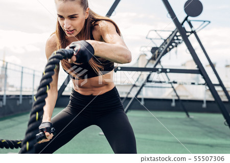 Woman doing fitness training using battle ropes Woman doing fitness training using battle ropes 55507306