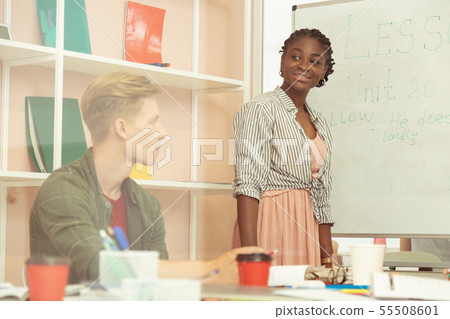 Cheerful young international teacher standing near board Cheerful young international teacher standing near board 55508601