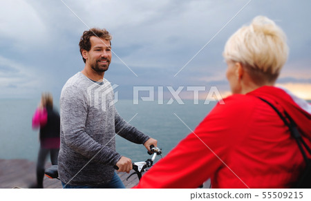 Couple with bicycles outdoors on beach, talking. Couple with bicycles outdoors on beach, talking. 55509215