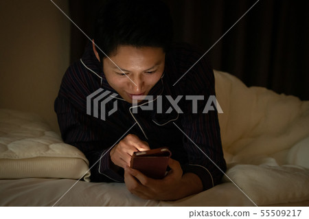 Japanese male blue light looking at smartphone before bedtime 55509217