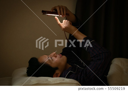 Japanese male blue light looking at smartphone before bedtime 55509219