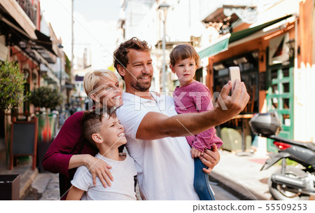 A young family with two small children standing outdoors in town, taking selfie. A young family with two small children standing outdoors in town, taking selfie. 55509253
