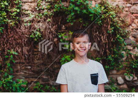 A portrait of small boy standing outdoors in front of old brick wall. A portrait of small boy standing outdoors in front of old brick wall. 55509254