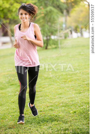 Dark-haired girl in sportswear running in the park. Dark-haired girl in sportswear running in the park. 55509537