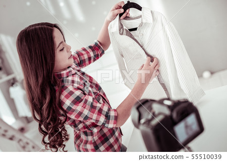 Joyful nice girl holding a hanger with her shirt Joyful nice girl holding a hanger with her shirt 55510039
