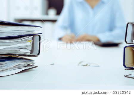 Binders with papers are waiting to be processed by business woman or bookkeeper back in blur Binders with papers are waiting to be processed by business woman or bookkeeper back in blur 55510542