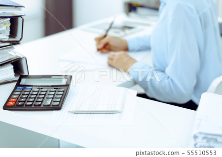 Calculator and binders with papers are waiting to be processed by business woman or bookkeeper back Calculator and binders with papers are waiting to be processed by business woman or bookkeeper back 55510553