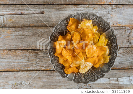 Silver bowl of mixed potato chips on wood Silver bowl of mixed potato chips on wood 55511569