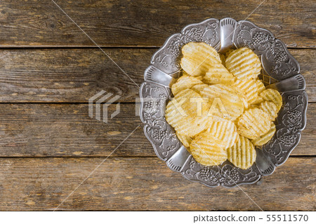 Potato chips in silver vintage plate on wooden Potato chips in silver vintage plate on wooden 55511570