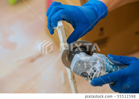 Worker cutting a tile using grinder at 55511598