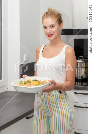 smiling young blond woman preparing the meal in 55515142
