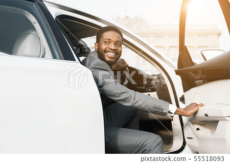 Smiling black businessman getting out of car 55518093
