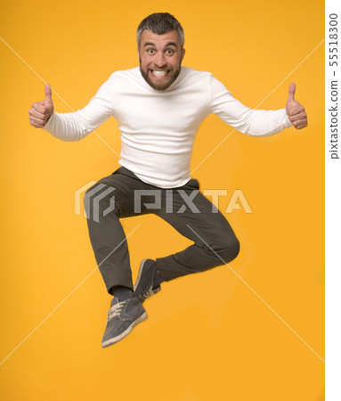 Joyful caucasian man jumping in the air with thumbs up 55518300