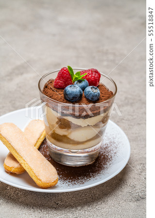 Classic tiramisu dessert with blueberries and raspberries and savoiardi cookies in a glass on 55518847