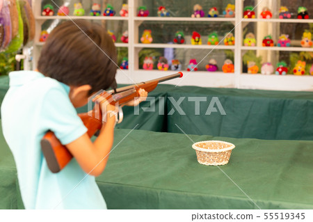 Boy shooting cork gun game at fair. Boy shooting cork gun game at fair. 55519345