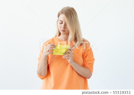 People, hobby and interests concept - Beautiful girl hold yellow retro camera on white background 55519351