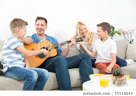 Happy caucasian family smiling, playing guitar and singing songs together at cosy modern home Happy caucasian family smiling, playing guitar and singing songs together at cosy modern home 55519843