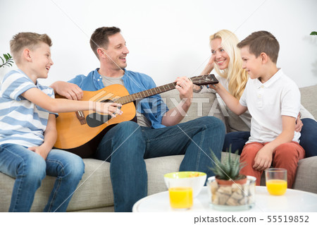 Happy caucasian family smiling, playing guitar and singing songs together at cosy modern home 55519852