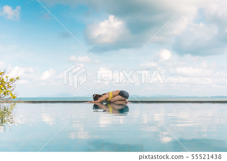 Woman relaxing in yoga over the pool on beach 55521438