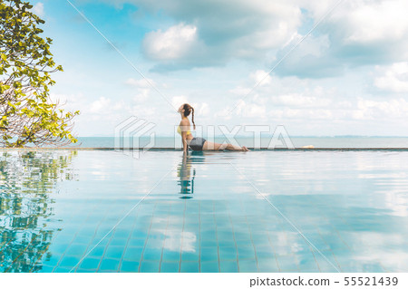 Woman relaxing in yoga over the pool on beach 55521439