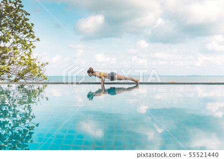 Woman relaxing in yoga over the pool on beach 55521440