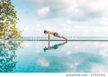 Woman relaxing in yoga over the pool on beach 55521441