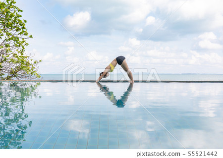 Woman relaxing in yoga over the pool on beach 55521442