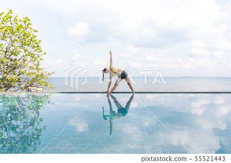 Woman relaxing in yoga over the pool on beach 55521443