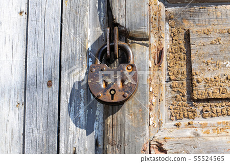 Old padlock on a wooden door. Heavy granary iron Old padlock on a wooden door. Heavy granary iron 55524565