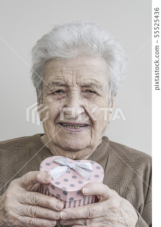 senior woman holding heart shaped gift 55525436