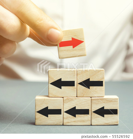 A man holds a wooden block with red arrow  55526592
