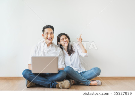 Asian couple sitting on floor using laptop in 55527959