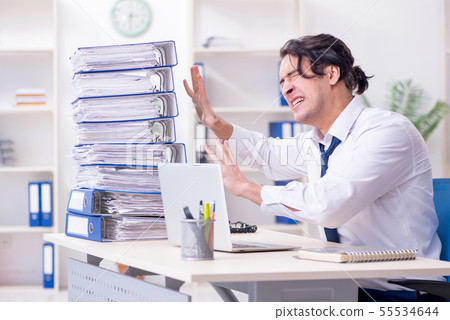 Young male employee unhappy with excessive work Young male employee unhappy with excessive work 55534644