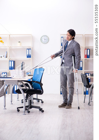 Leg injured male employee working in the office Leg injured male employee working in the office 55535309