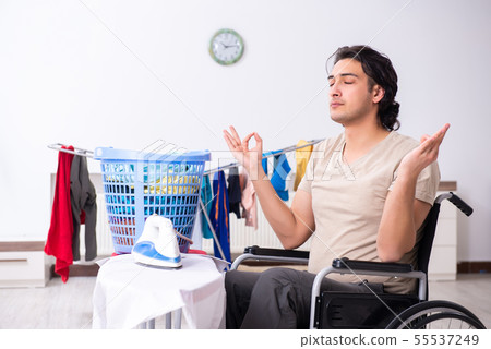 Young man in wheel-chair doing ironing at home Young man in wheel-chair doing ironing at home 55537249
