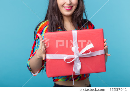 Close-up pf beautiful young brunette girl holding a red gift box in her hands while standing against Close-up pf beautiful young brunette girl holding a red gift box in her hands while standing against 55537941