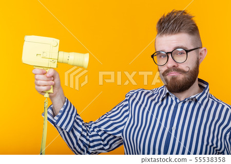 Unidentified young man with a yellow camera with a mustache and a beard on a yellow background Unidentified young man with a yellow camera with a mustache and a beard on a yellow background 55538358