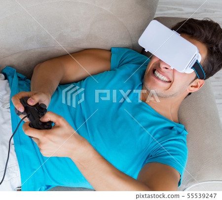 Young man wearing VR glasses relaxing on couch sofa Young man wearing VR glasses relaxing on couch sofa 55539247