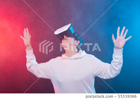 Passionate middle-aged woman in sweater is watching new film with glasses of virtual reality on red Passionate middle-aged woman in sweater is watching new film with glasses of virtual reality on red 55539366