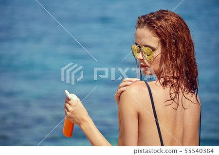 sexy young woman on the beach applying sun cream 55540384