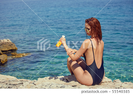 sexy young woman on the beach applying sun cream 55540385