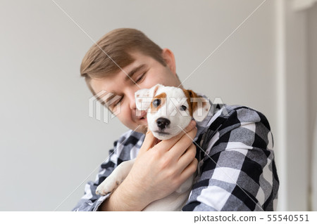 people, pets and animals concept - close up of young man hugging jack russell terrier puppy on white 55540551