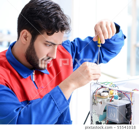 Young repairman fixing and repairing microwave oven 55541018