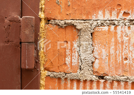 A close up of an old red brick wall and a band of a brown painted metal garage door A close up of an old red brick wall and a band of a brown painted metal garage door 55541419