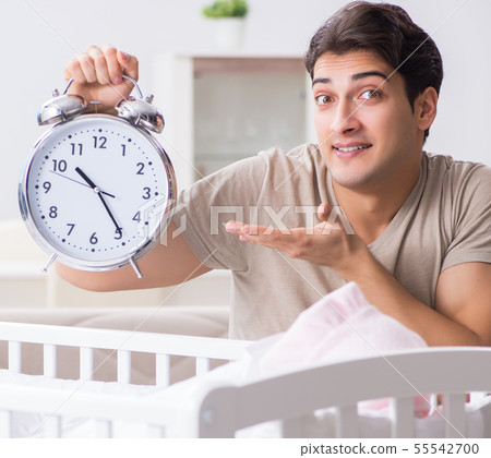Young dad with clock near newborn baby bed cot Young dad with clock near newborn baby bed cot 55542700