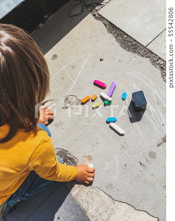 Toddler in jeans draws with crayons on the asphalt Toddler in jeans draws with crayons on the asphalt 55542806