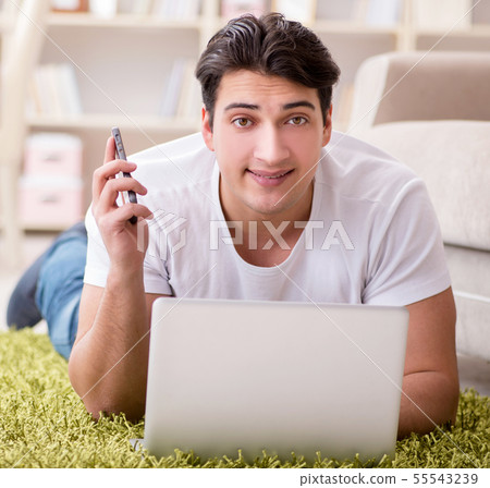 Man working on laptop at home on carpet floor Man working on laptop at home on carpet floor 55543239