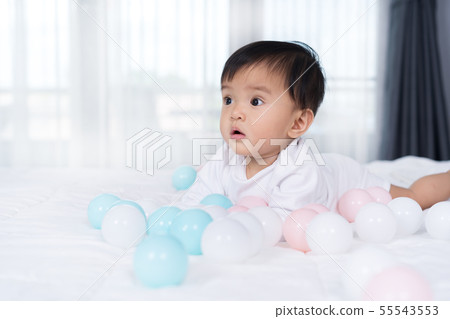 cheerful baby playing color ball on bed cheerful baby playing color ball on bed 55543553
