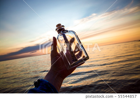 Message in the bottle against the Sun setting down 55544857