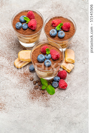 Classic tiramisu dessert with blueberries and raspberries and savoiardi cookies in a glass on 55545906